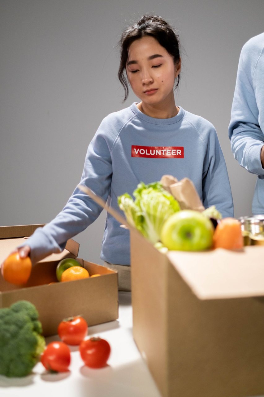 Free A volunteer organizing donation boxes filled with fresh fruits and vegetables. Stock Photo