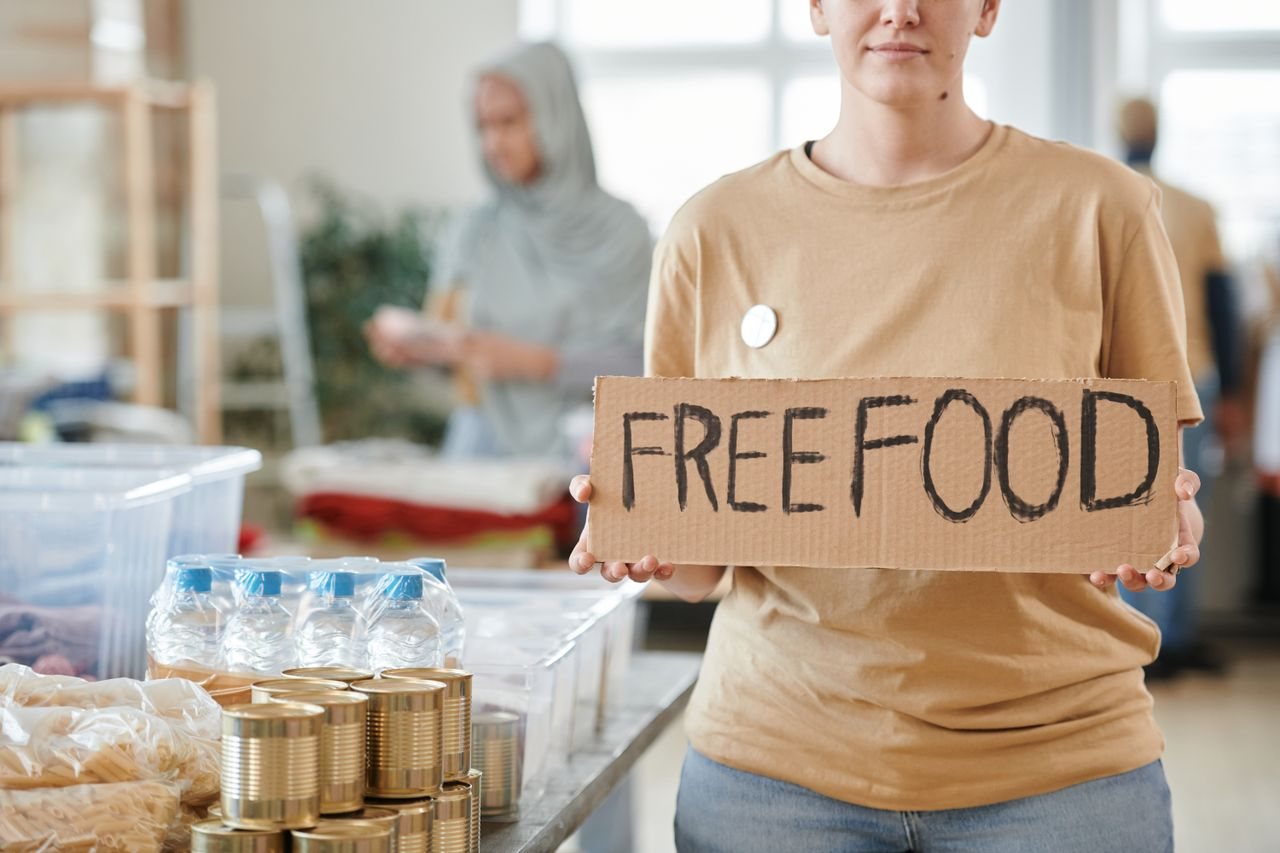 Free Volunteer holding a free food sign at a donation center, promoting charity and aid. Stock Photo